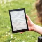 kobieta w ogrodzie trzymająca w ręku czytnik e-booków