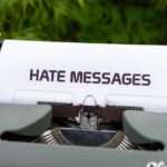 Arkusz papieru z napisem "HATE MESSAGES" włożony do maszyny do pisania.