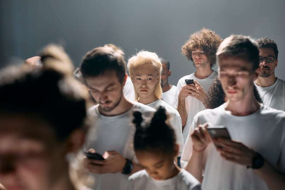 Grupa osób w białych koszulkach korzysta ze smartfonów w słabym oświetleniu.