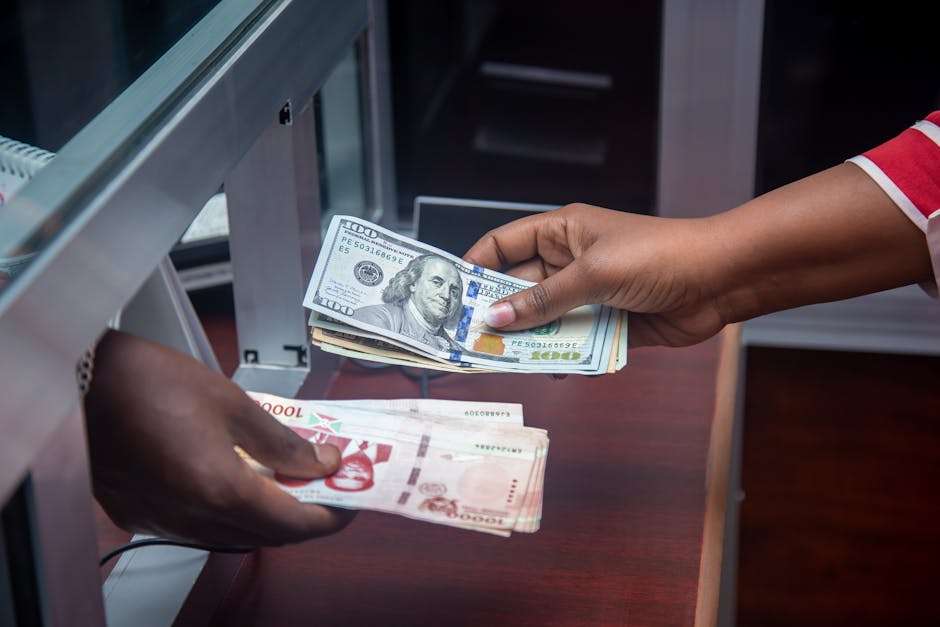 Dłonie przekazują sobie plik banknotów dolarów amerykańskich oraz waluty lokalnej w kantorze.