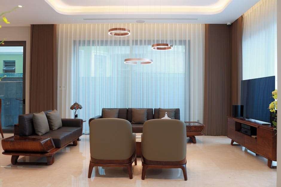 Nowoczesny salon z ciemnymi meblami, dwoma fotelami i wiszącymi okrągłymi lampami.