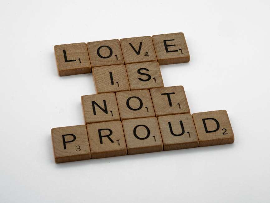 Drewniane płytki do gry w Scrabble układające się w napis LOVE IS NOT PROUD.