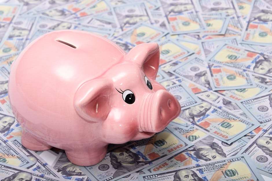 Różowa świnka skarbonka stojąca na wielu banknotach studolarowych.