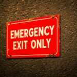 czerwona tablica z napisem "EMERGENCY EXIT ONLY"